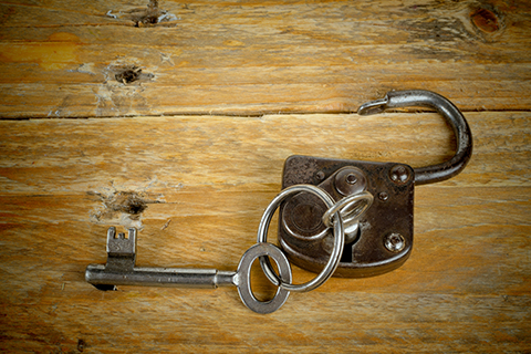 An open padlock with a key inside on a wooden background, representing the escape rooms at Escape Blue Ridge in Blue Ridge, Georgia. Guests staying at Xplorie participating properties can enjoy a free admission to the room of their choice.