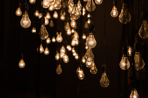 A view of a multitude of vintage light bulbs hanging in a dark room, representing the escape rooms at Escape The Island in Galveston, Texas. Guests staying at Xplorie participating properties can enjoy a free admission to the room of their choice.
