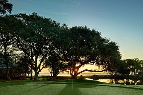 Beautiful sunset as seen through the trees at Osyer Reef Golf Club at Hilton head Island, South Carolina, where guests staying at Xplorie participating properties can enjoy a free round of golf.