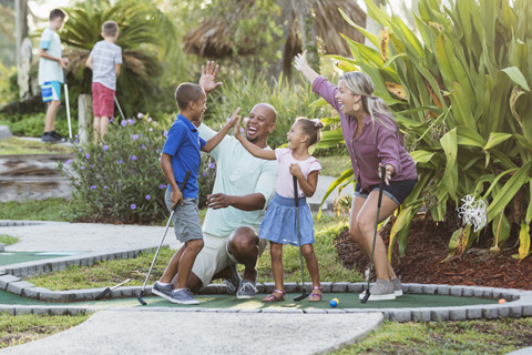 Family playing at a Jamaican-themed golf course at Runaway Bay Miniature Golf in Garden City, South Carolina, where guests staying at Xplorie participating properties can enjoy a free round of eighteen hole golf.