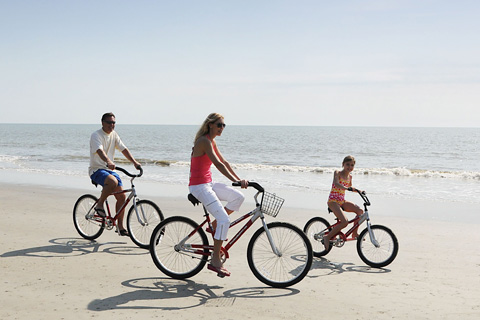 A young man and woman enjoying their bike rentals from TIMS in Tybee Island, Georgia, which is available for free to guests staying at Xplorie participating properties.