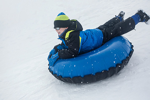 A boy slides on a tube in the snow at Wolf Ridge Ski Resort in Mars Hill, North Carolina, where guests staying at Xplorie participating properties can enjoy a free lift ticket.